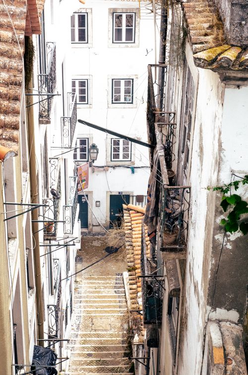 Free Explore a picturesque narrow alley in Lisbon with traditional architecture and rustic charm. Stock Photo