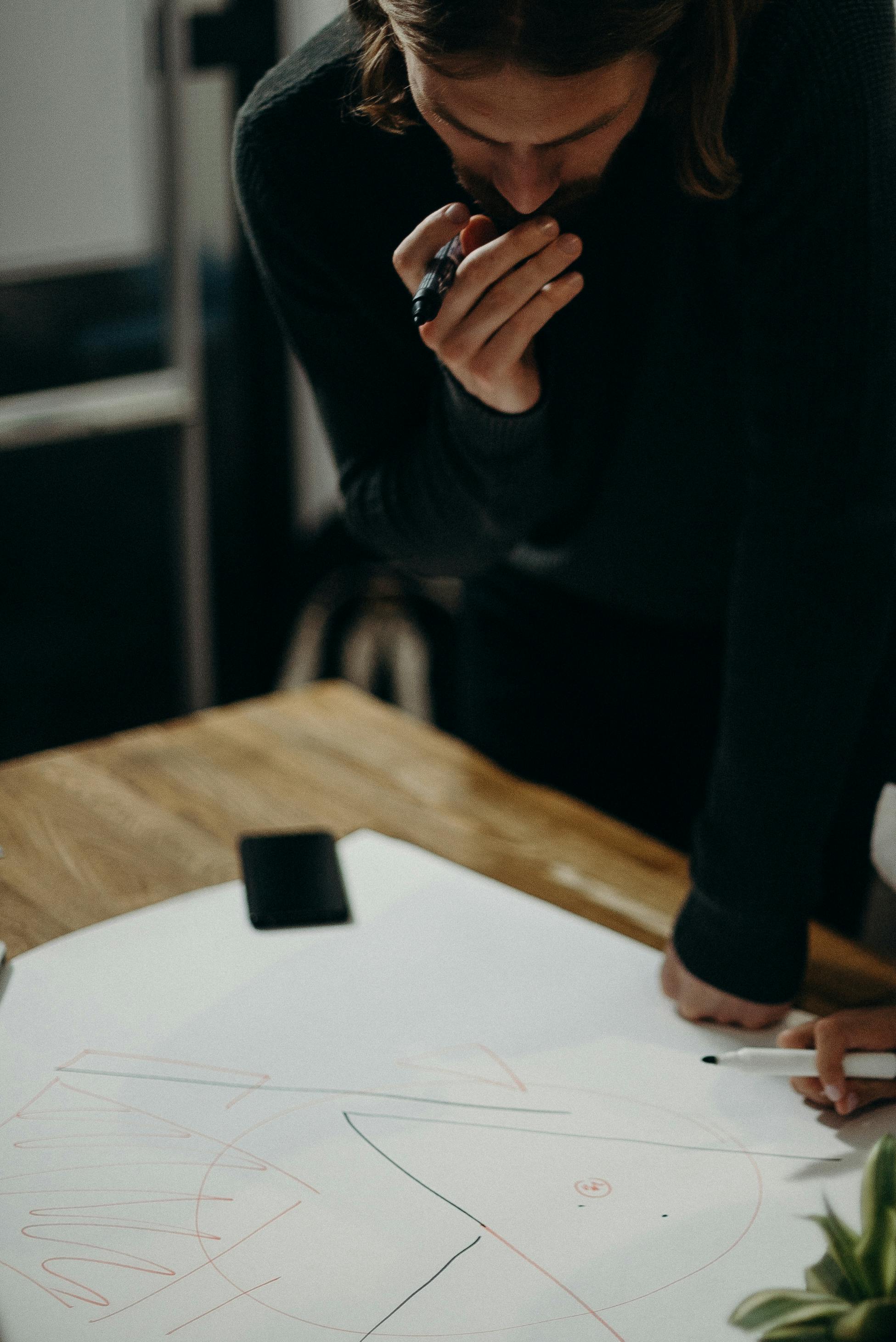 创意专业人士在现代办公桌上用纸笔勾画想法