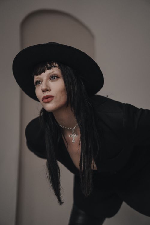 Free Chic portrait of a woman in black attire and hat, featuring ornate jewelry, exuding edgy fashion style. Stock Photo