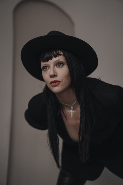 Free Portrait of a woman in dark attire and hat, exuding modern elegance. Stock Photo