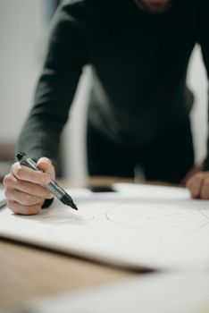 一个男人在室内用记号笔在纸上作画的特写