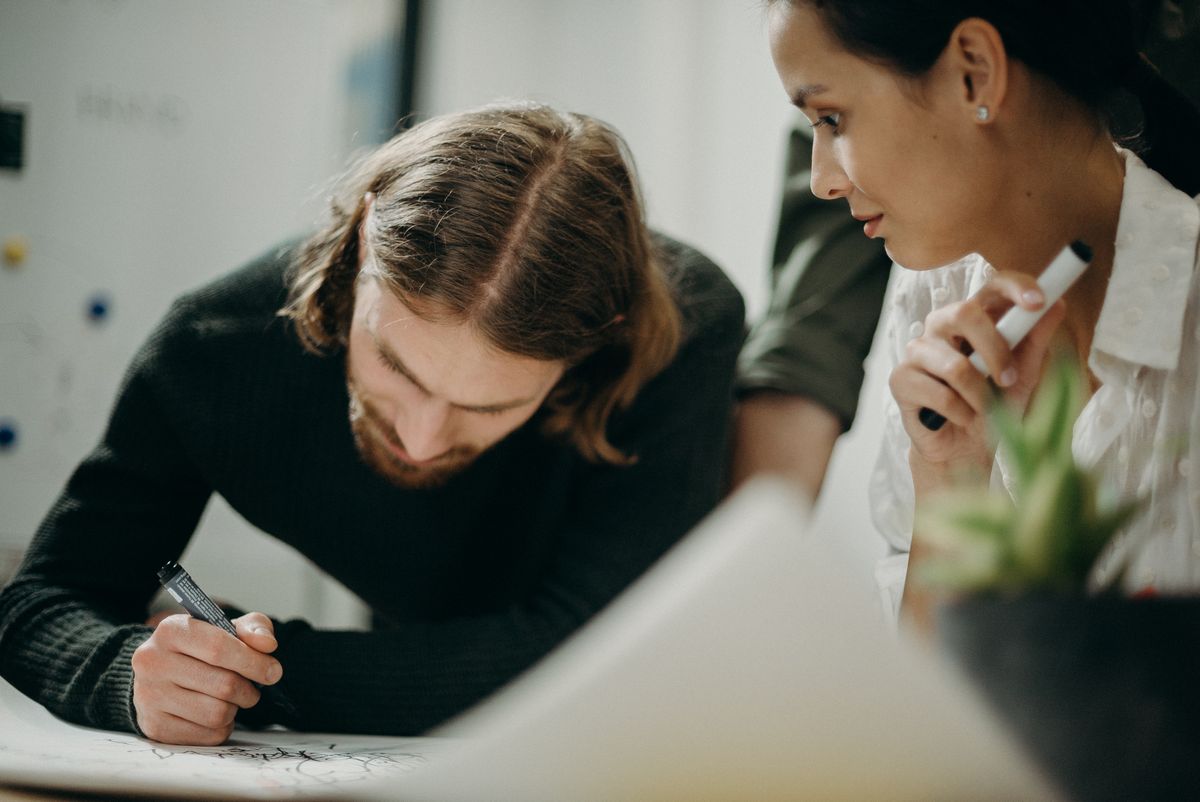 Two professionals planning on paper at a desk while weighing the Salesforce admin vs developer path