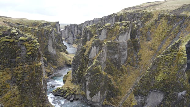 A breathtaking view of Fjadrargljufur Canyon's rugged cliffs and winding river in Iceland.