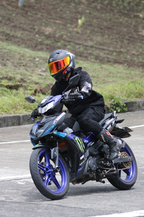 Free A motorcyclist wearing full gear rides a sportbike on a curved outdoor road. Stock Photo