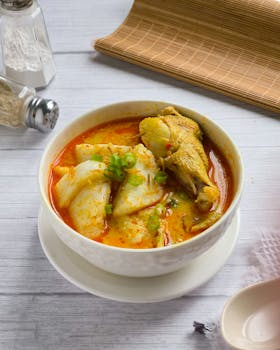 A vibrant bowl of lontong kari with chicken curry, rich in spices.