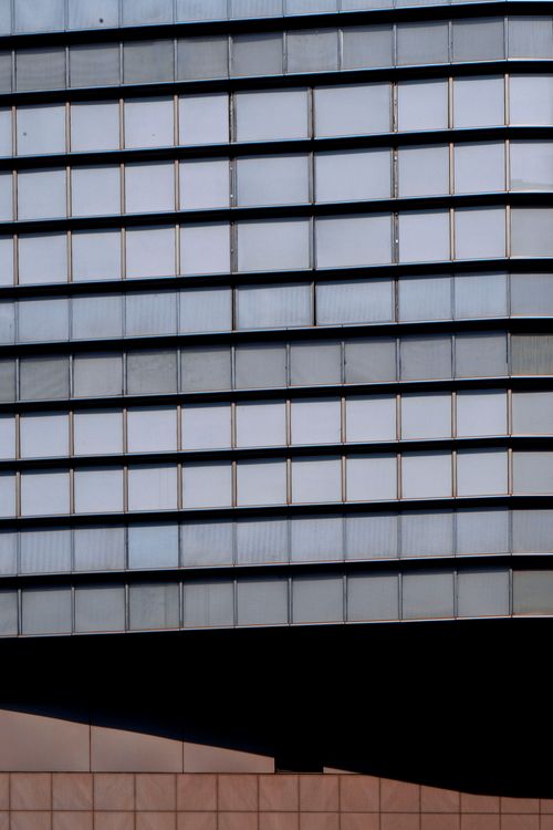 Free Low angle shot of a sleek modern building with a glass facade, reflecting urban architecture. Stock Photo