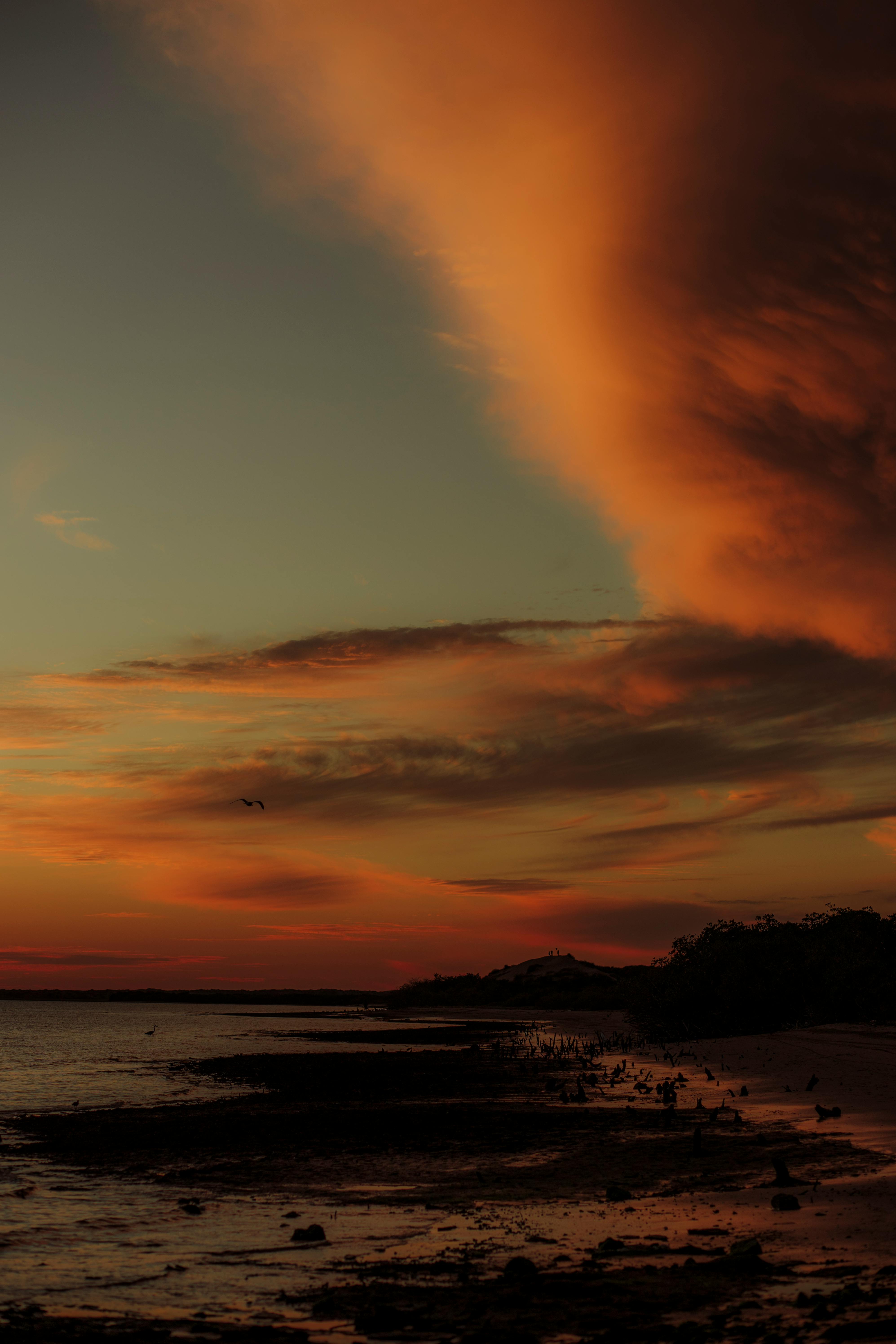 Capture of a stunning sunset with vibrant orange clouds over a calm beach in Sinaloa, Mexico.