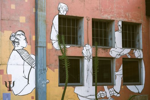 Artistic mural on university wall in Córdoba, featuring abstract human figures. Outdoor scene.