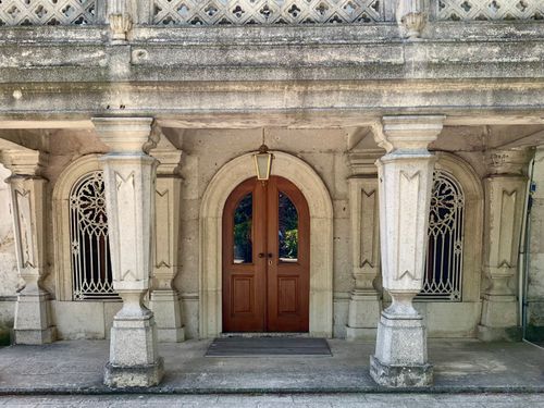 Free Elegant stone facade with arched wooden door and decorative columns. Stock Photo