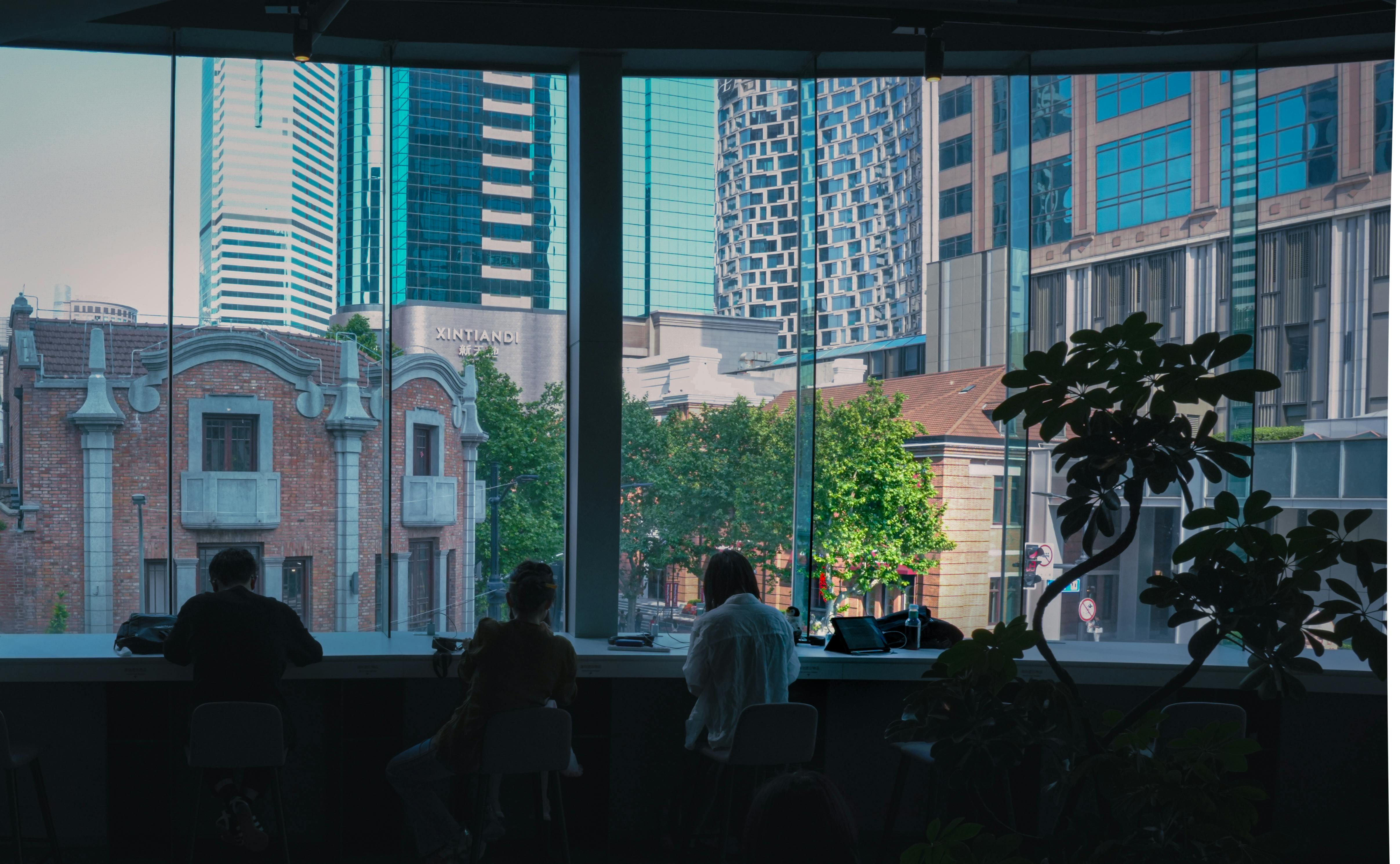 People working in a modern coworking space with panoramic city views in Xintiandi, Shanghai.