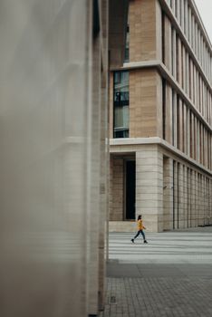 一个人走过当代城市建筑的立面，展示了现代建筑的时尚设计