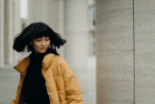 Selective Focus Photo of Woman in Mustard Yellow Bubble Jacket Posing with Her Eyes Closed