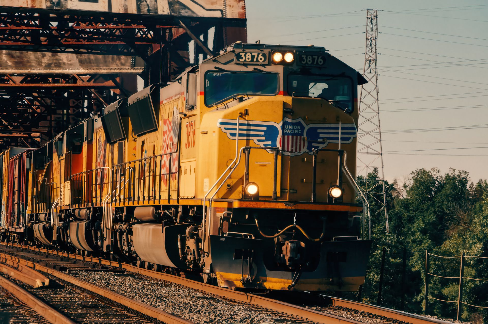 A Union Pacific freight train crossing an industrial bridge against a clear sky backdrop.