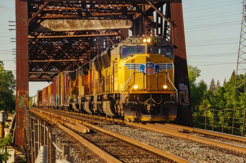 Free Dynamic image of a freight train crossing a steel bridge with vibrant colors at sunset. Stock Photo