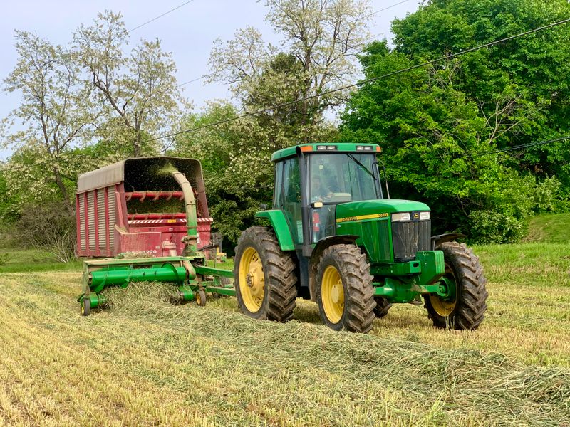 Tractor harvesting on commercial farmland — Olives Organic Foods sources directly from certified producers across Uganda