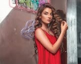 一位穿着红色连衣裙的卷发美女在霓虹灯下摆姿势