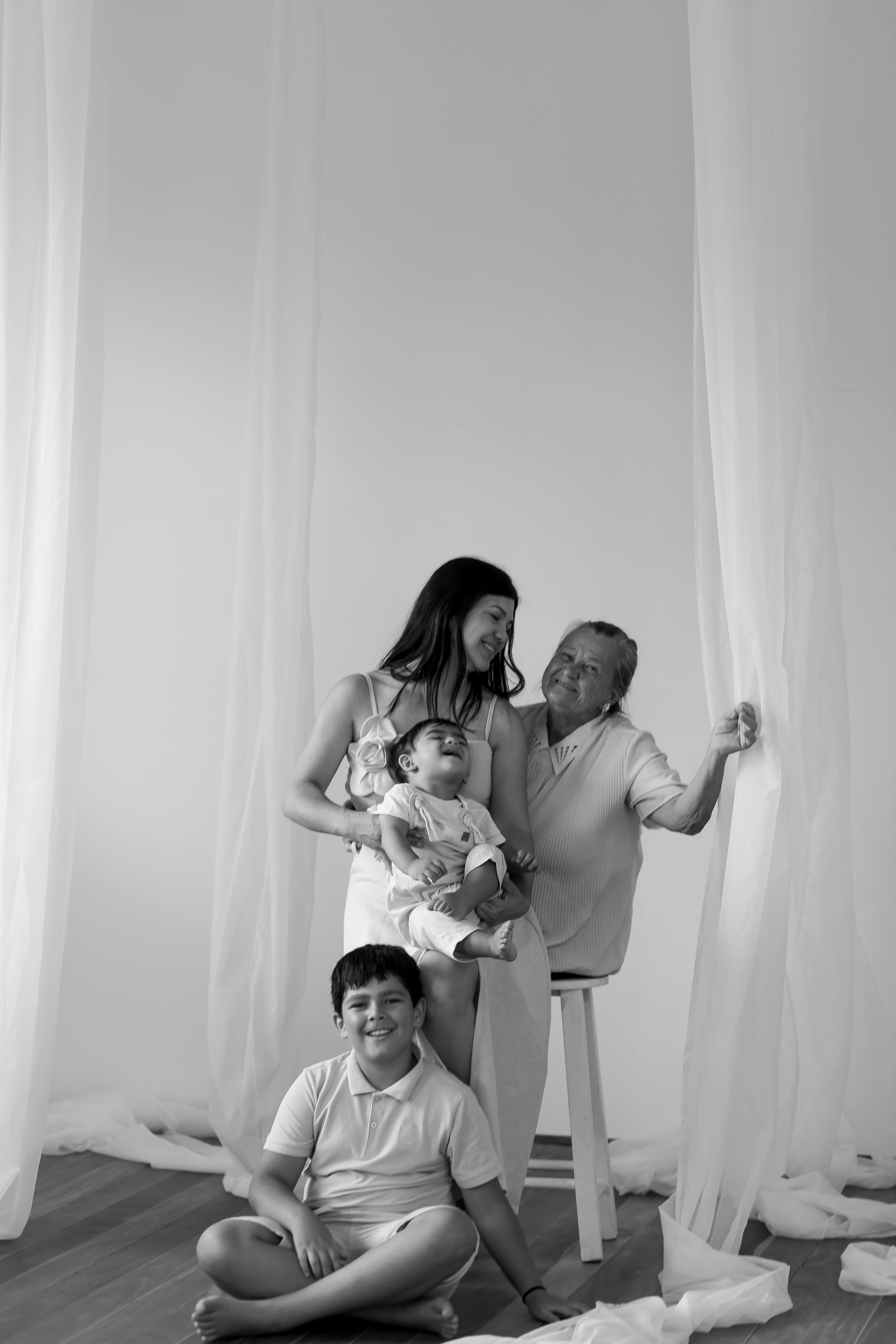 A touching monochrome image of a multi-generational family moment indoors.