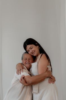 Heartwarming moment of a loving embrace between an adult and senior indoors.