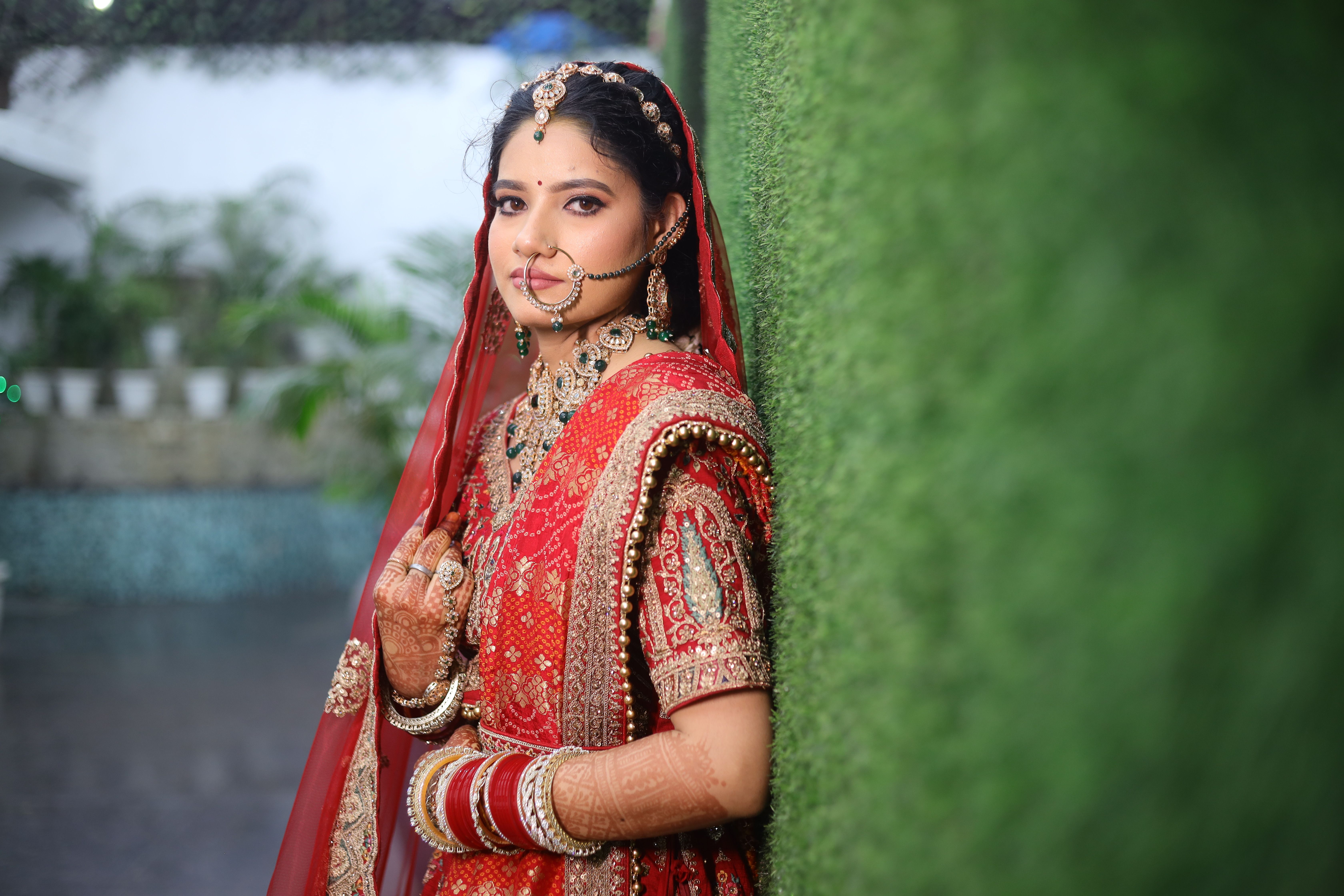 Beautiful Indian bride in traditional red wedding attire with intricate jewelry and henna designs.