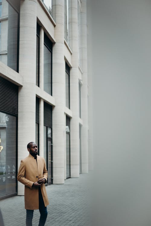 Photo of Man in Brown Coat Posing Outside Building