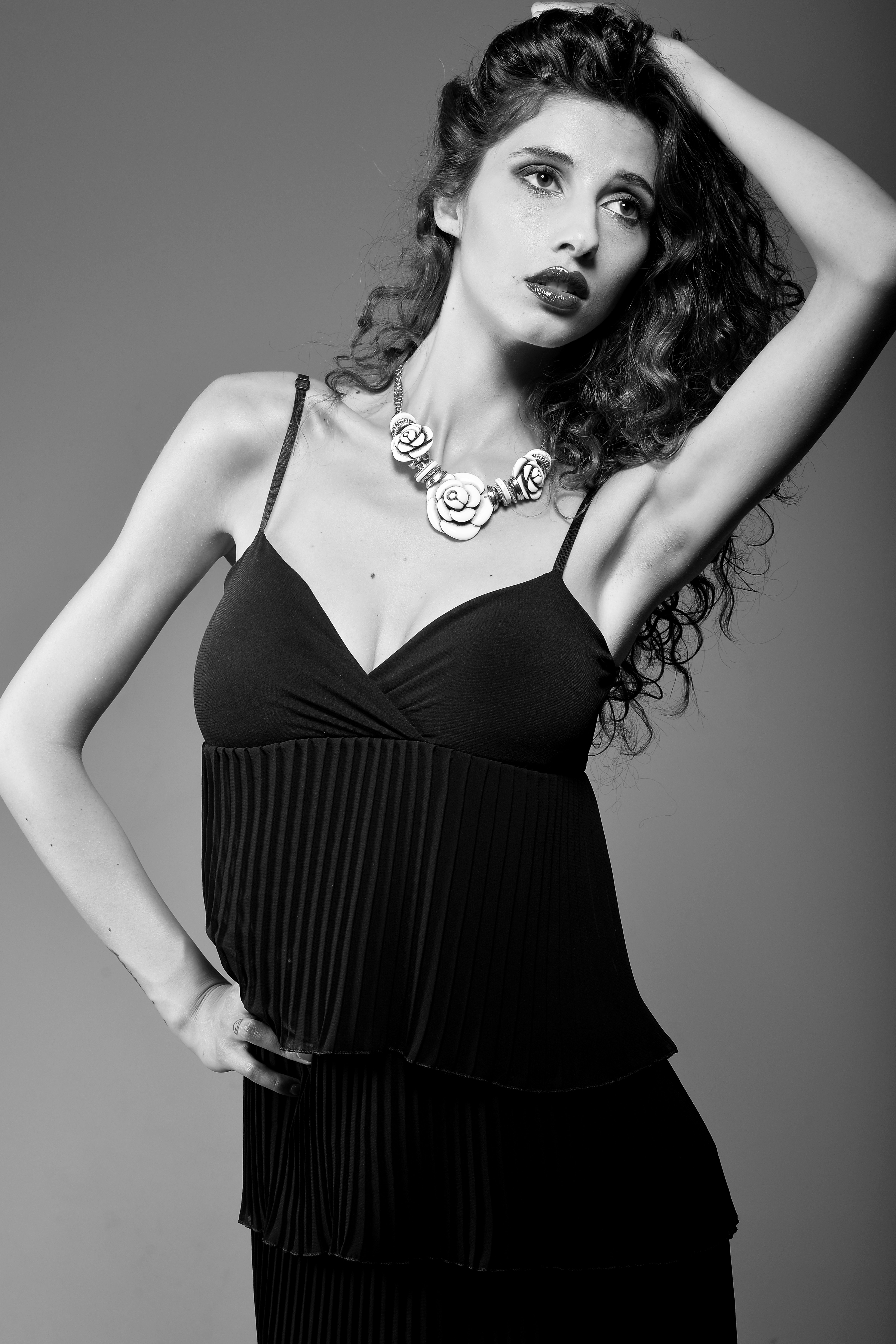 Striking black and white portrait of a woman posing stylishly with a floral necklace.