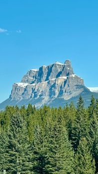 Stunning view of Castle Mountain with clear skies and lush pine forest in Banff.