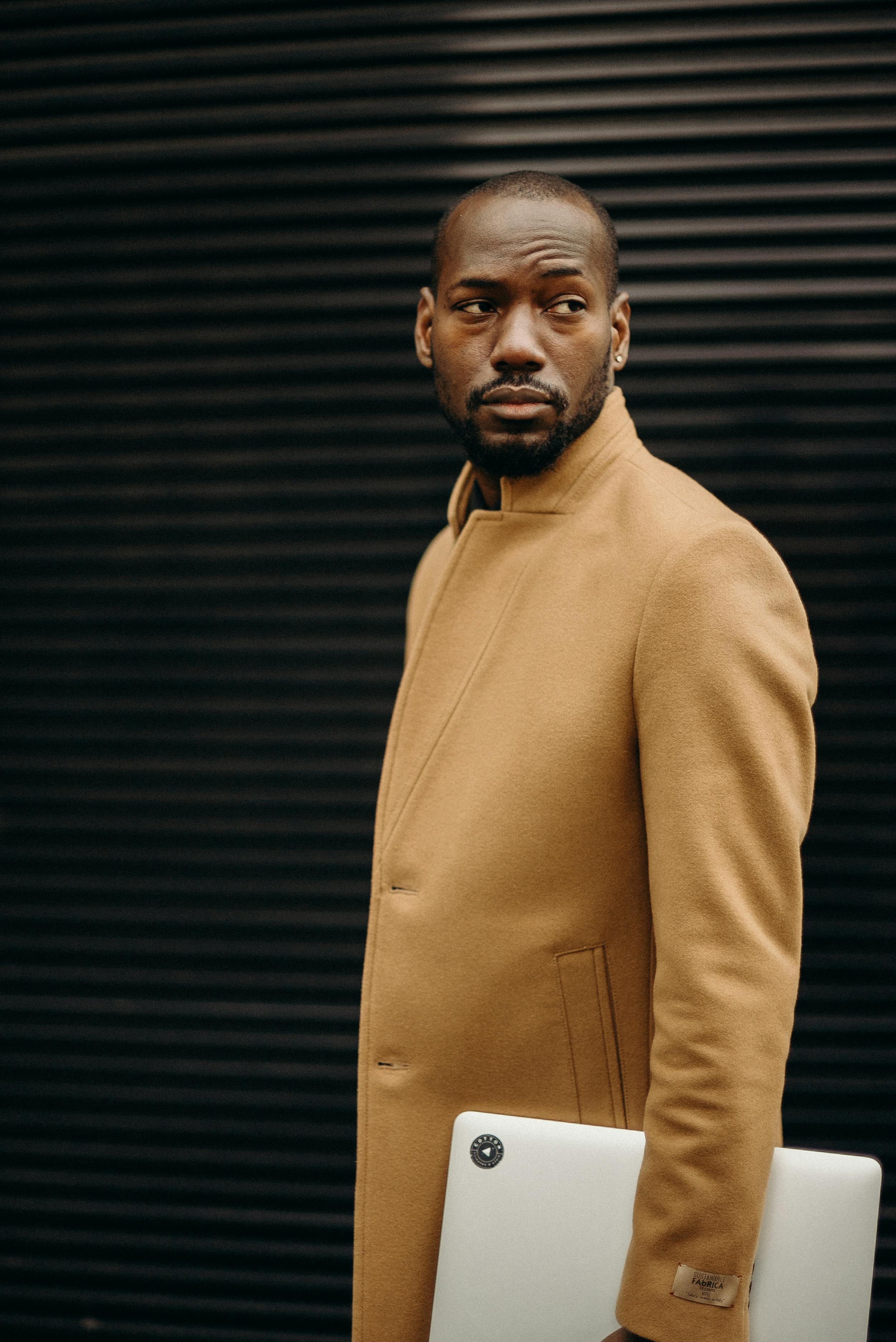 在城市环境中，时尚成人摆姿势，身旁放着笔记本电脑