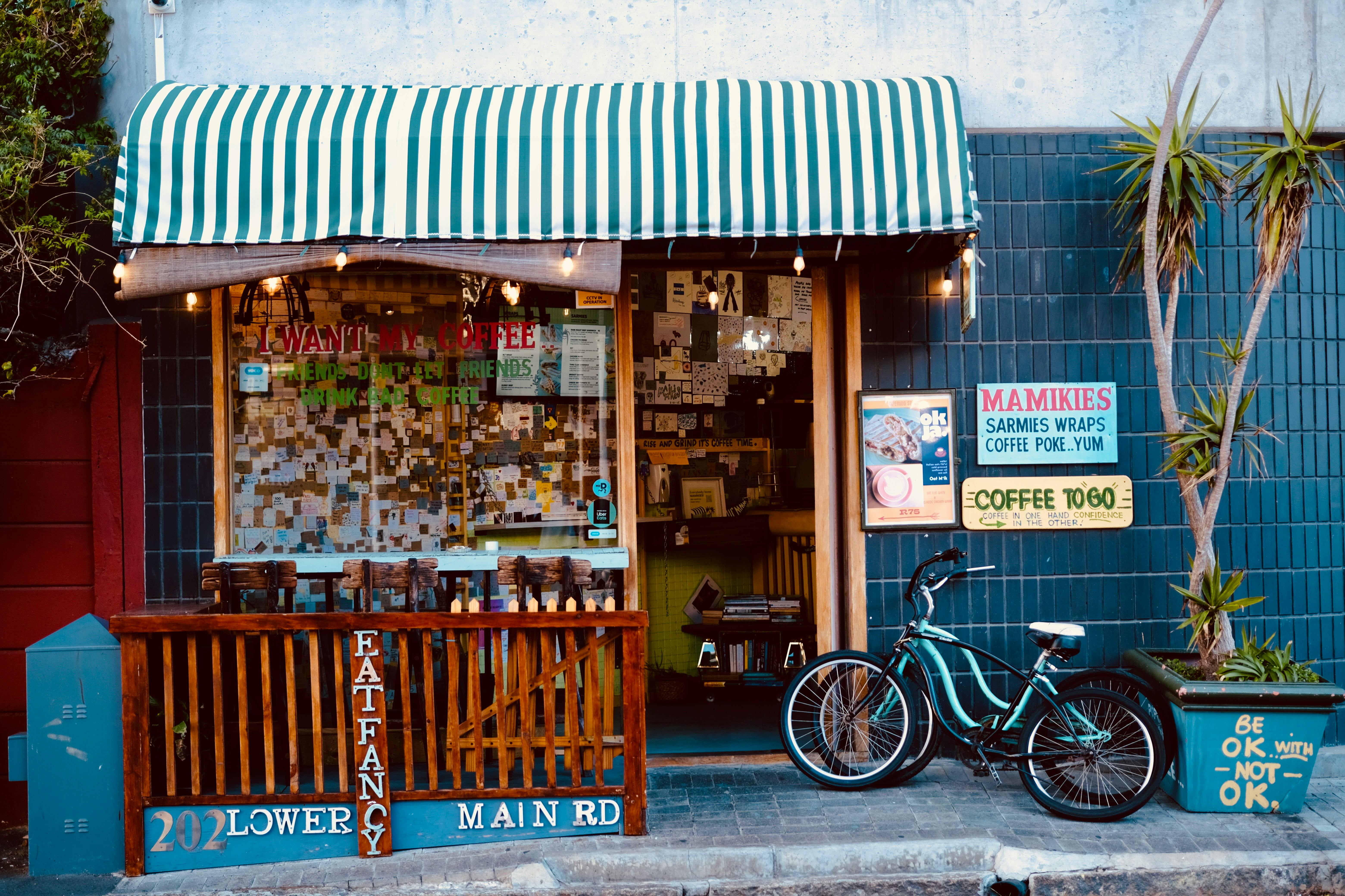 Cozy street cafe storefront with striped awning, bike, and eclectic signage.