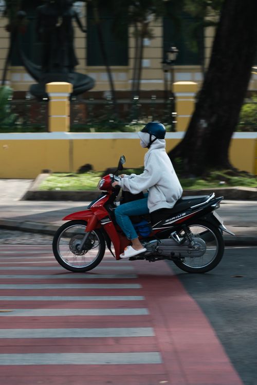 Free A person riding a red motorcycle over zebra crossing in an urban setting. Stock Photo