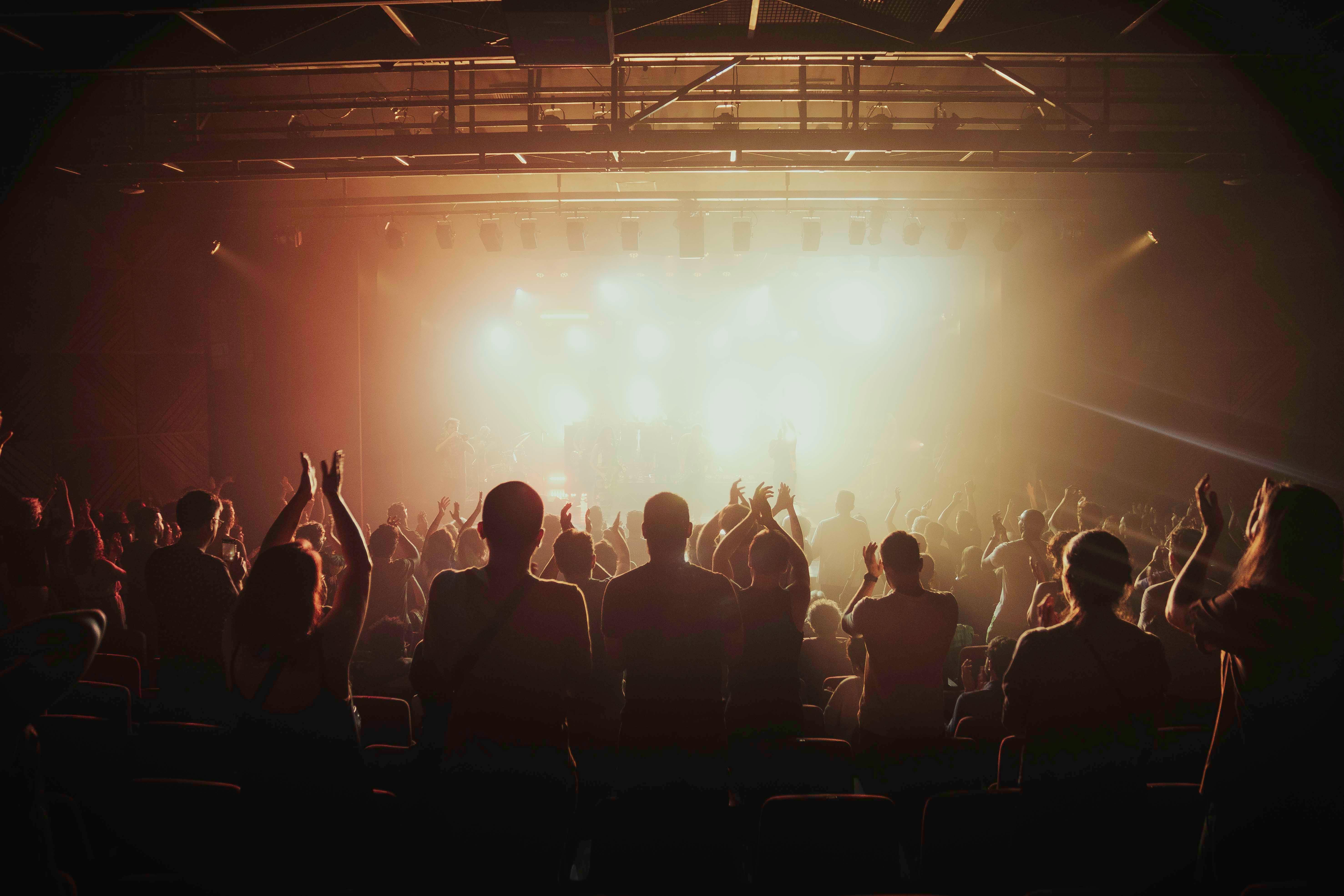 Gratis Livligt publikum jubler under livekoncert i et svagt oplyst indendørs spillested. Lagerfoto