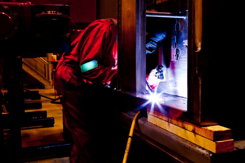 Soudeur professionnel en combinaison travaillant avec des etincelles dans un atelier