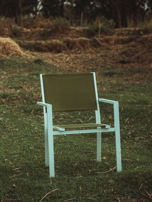 Free A lone outdoor chair placed in a grassy field, offering a serene and minimalist aesthetic. Stock Photo