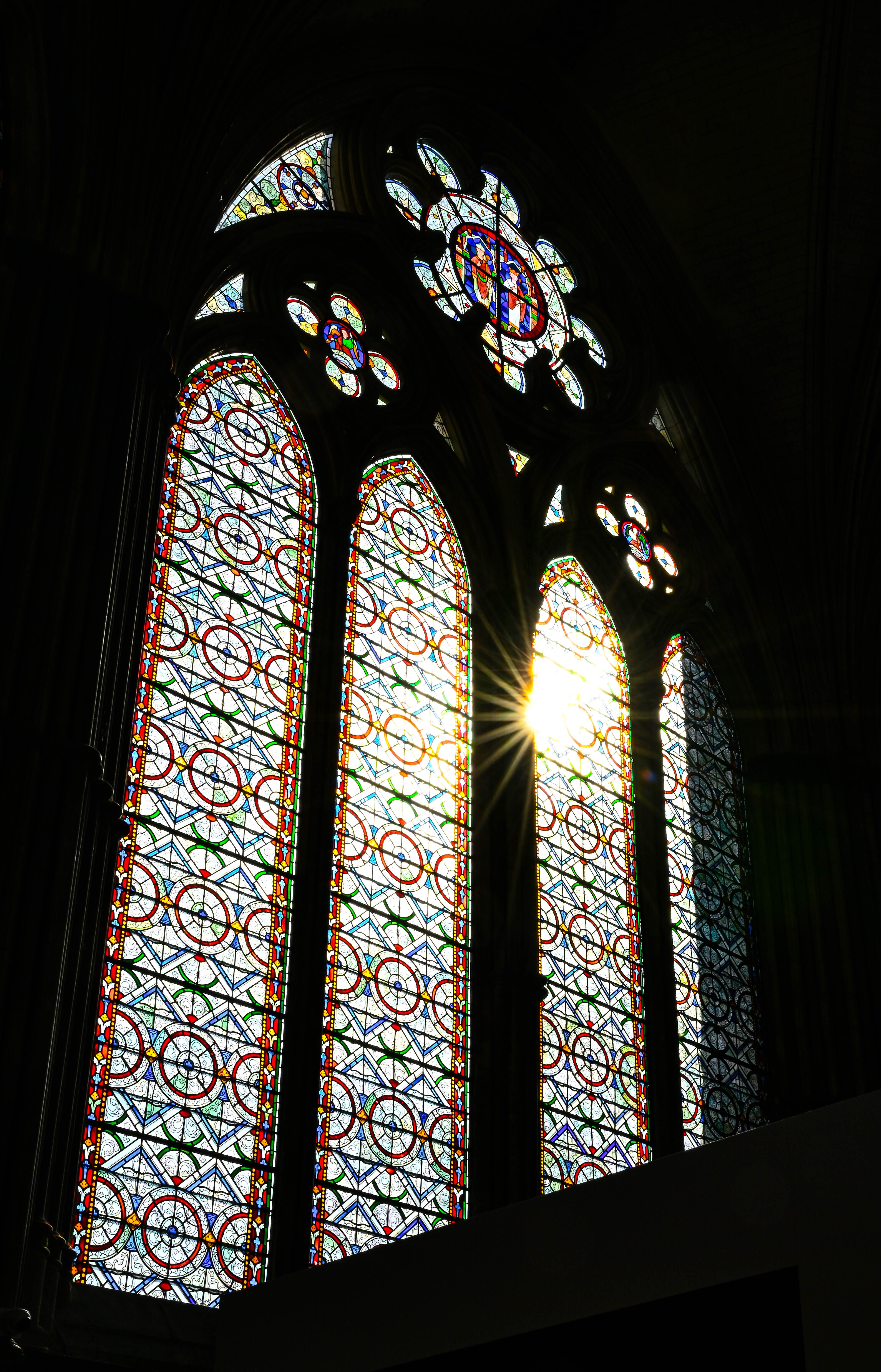 Beautiful sunlight streaming through a gothic stained glass window inside a cathedral.