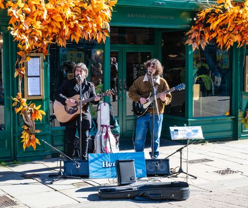 Free Two street musicians performing outside a decorated British chophouse in autumn. Stock Photo