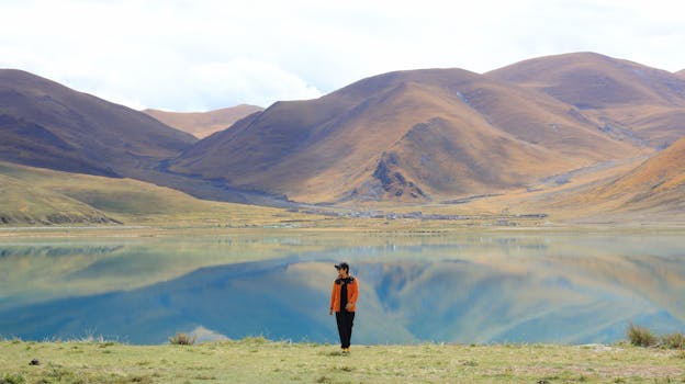 A tranquil scene of a person by a reflective lake with mountains in Shannan City, China.
