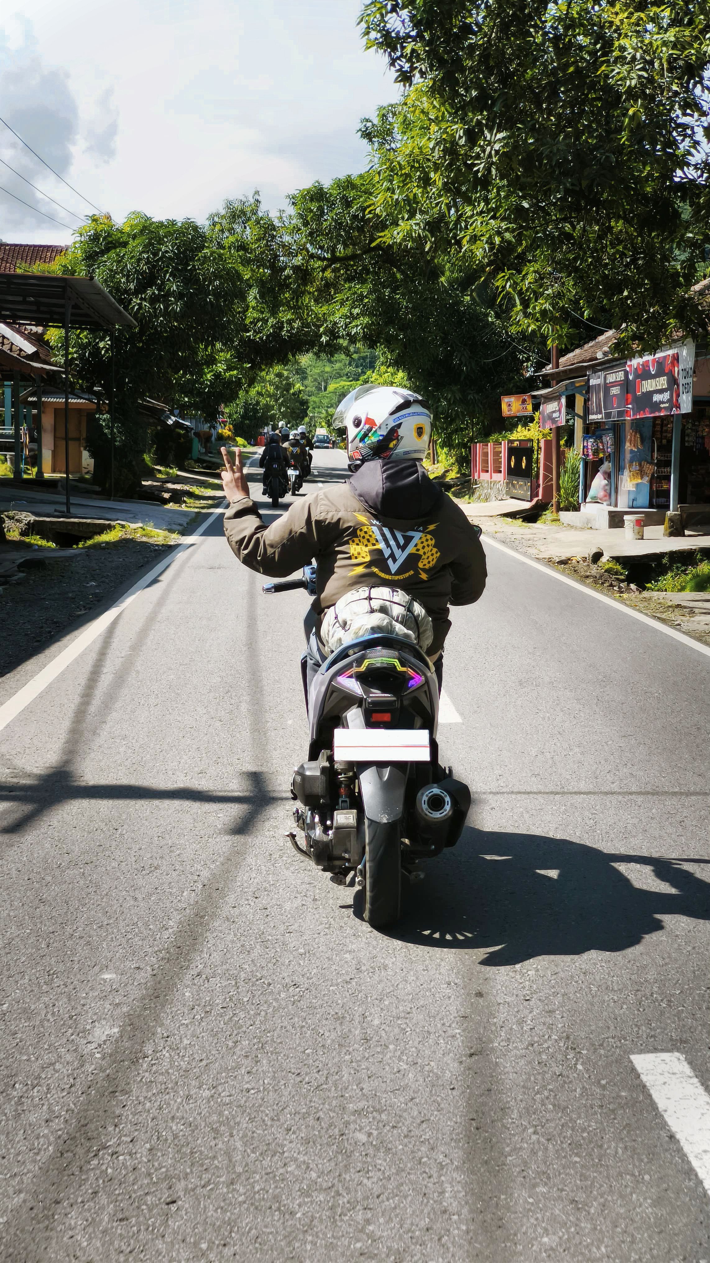 A motorcyclist rides through a lush Indonesian landscape, showcasing adventure and exploration.