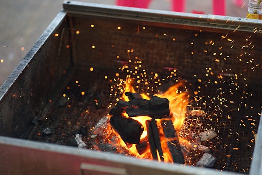 Lively outdoor charcoal grill fire with glowing embers and sparks.