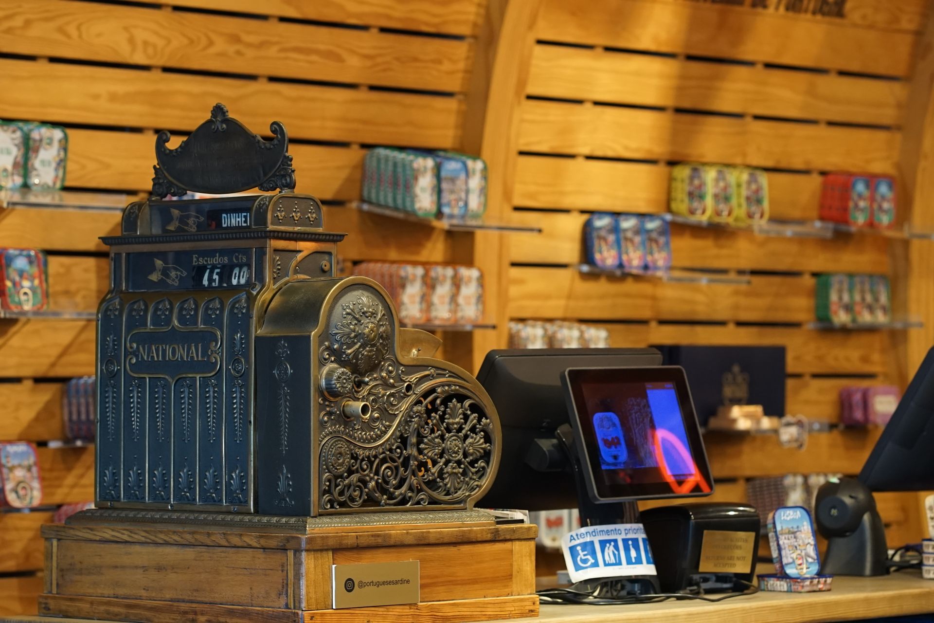 Old-fashioned cash register displayed in a contemporary store with modern payment systems.
