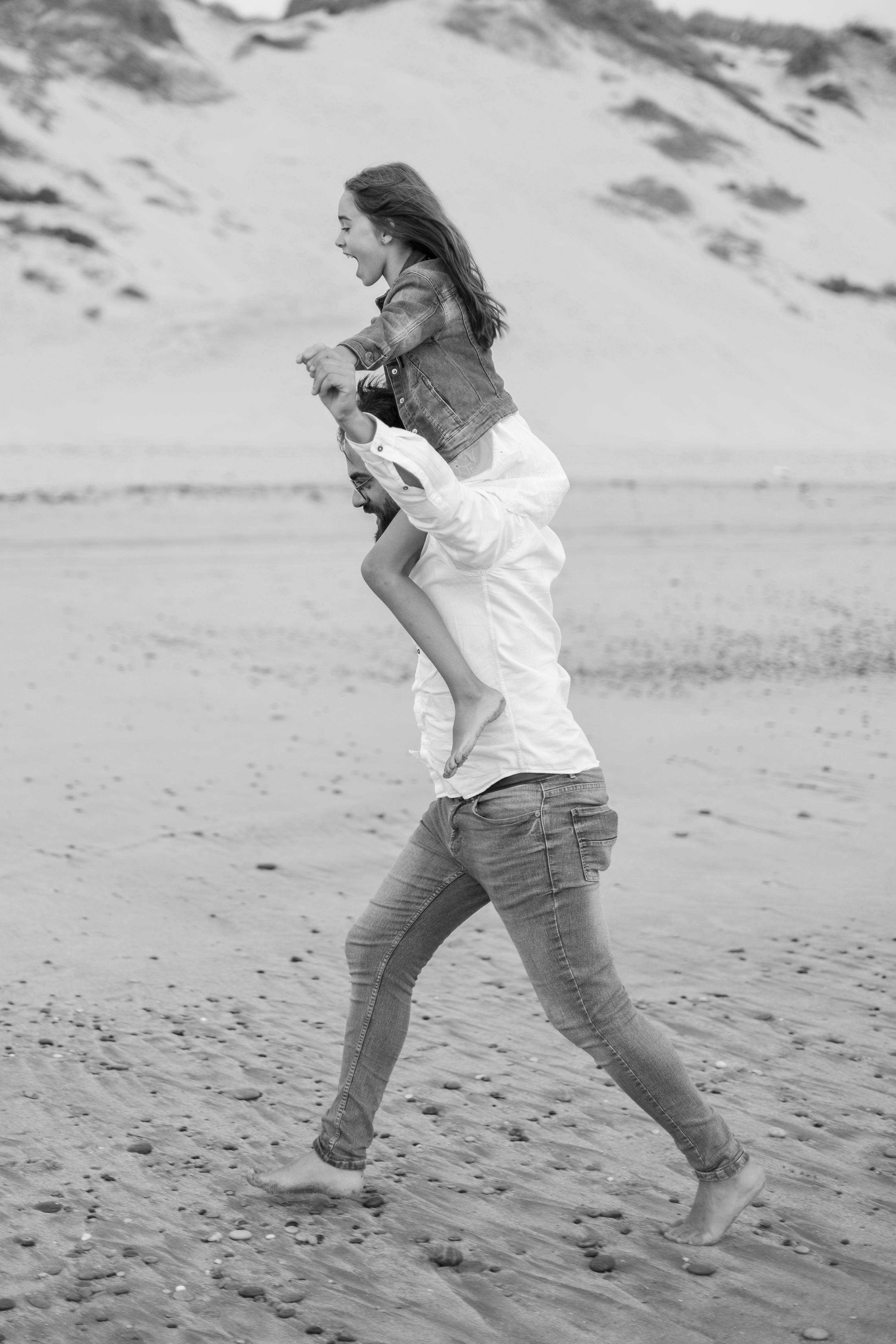 Father and daughter enjoying a playful piggyback ride on a beach in Ponte de Lima.