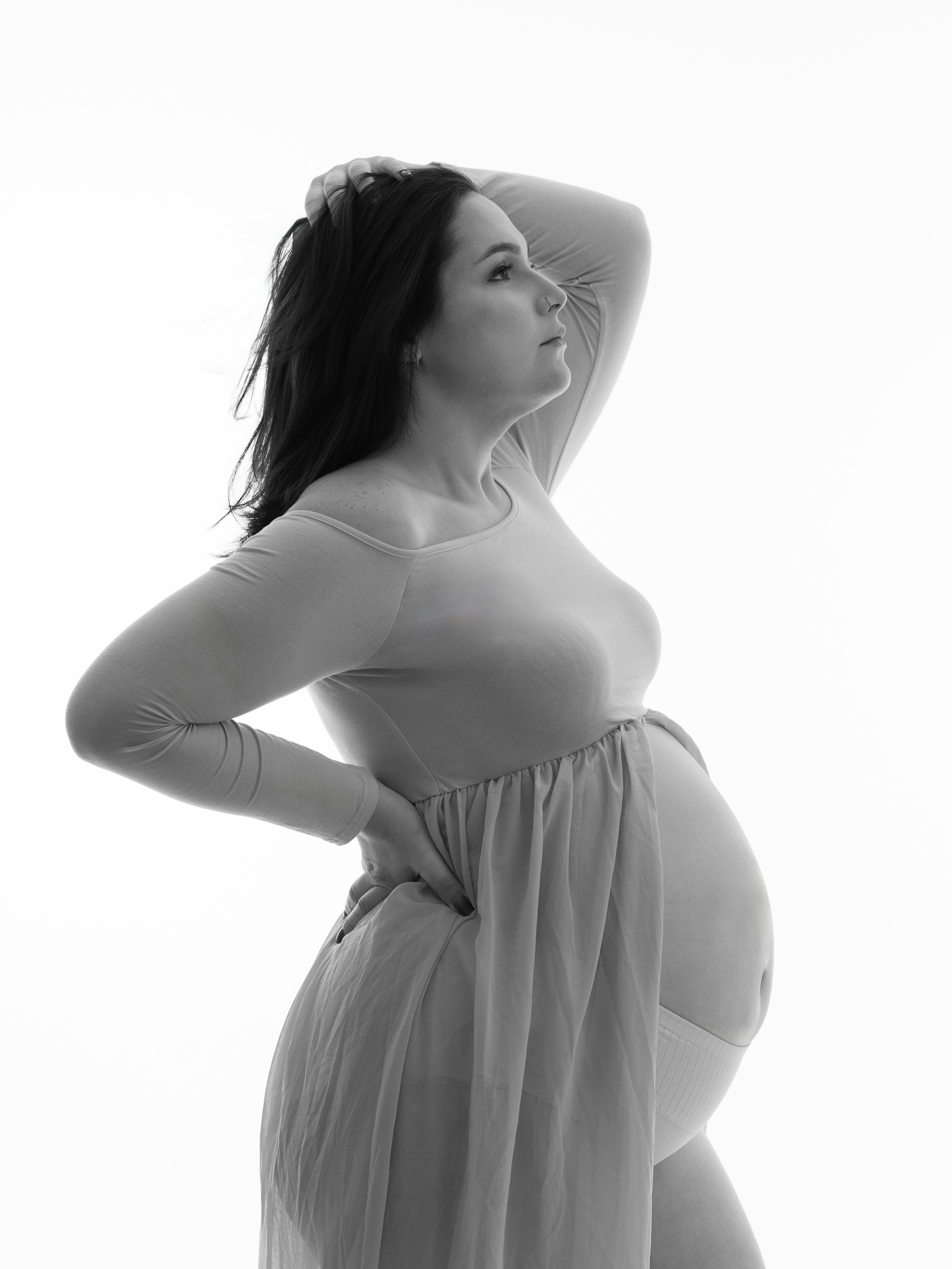 Graceful black and white photo of a pregnant woman in an elegant pose.