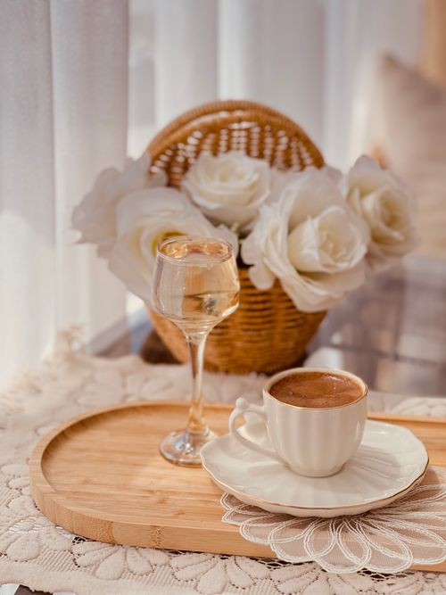 Free A serene coffee setting indoors with white roses and wine, bathed in natural light, perfect for a relaxed lifestyle vibe. Stock Photo