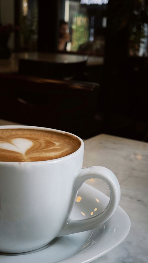 Free Latte with elegant art on a marble table in a cozy coffee shop. Stock Photo