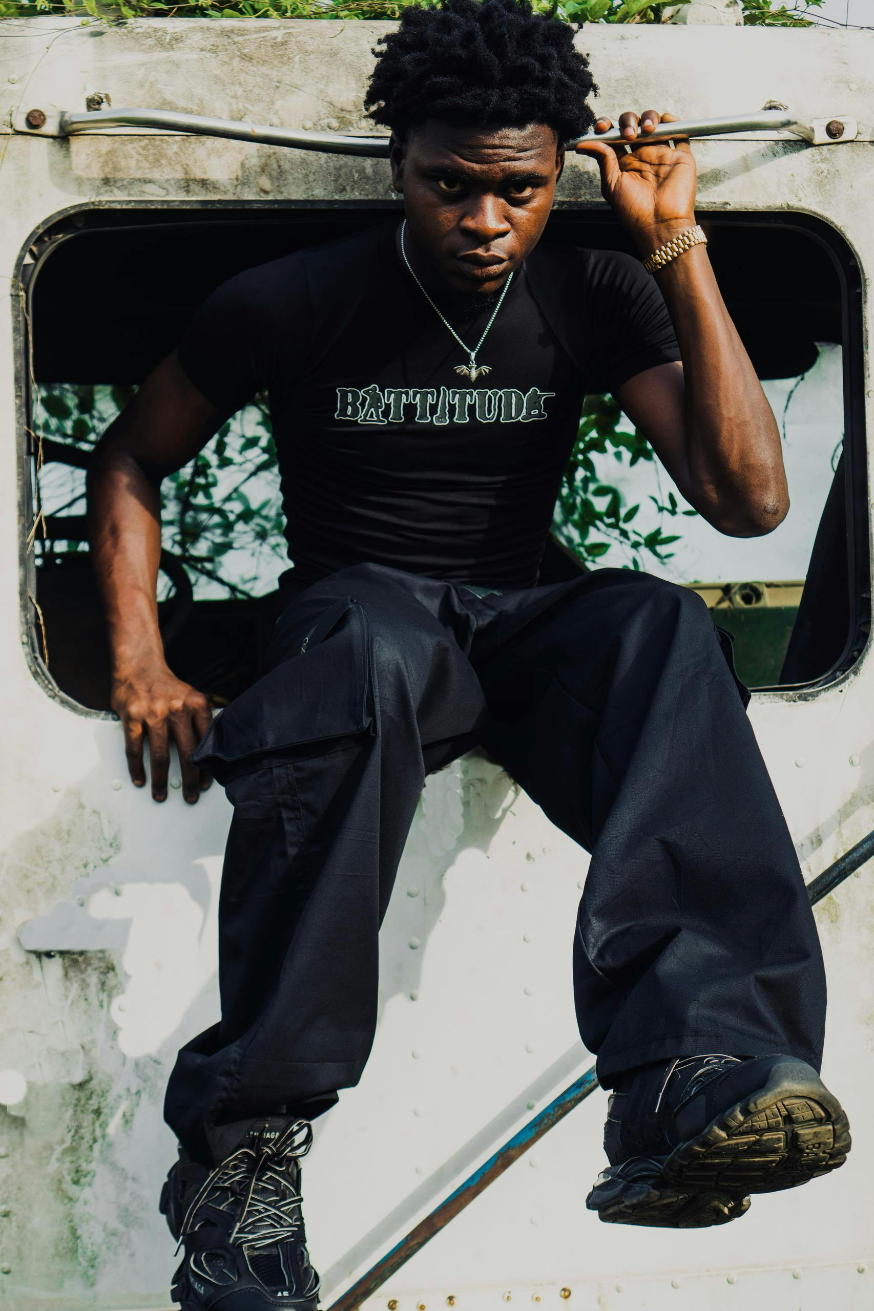 Free A young man with a confident expression sits in an old window frame wearing black attire. Stock Photo