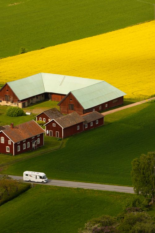 Free A picturesque aerial view of a farm in Gränna, Sweden with vibrant fields and red barns. Stock Photo
