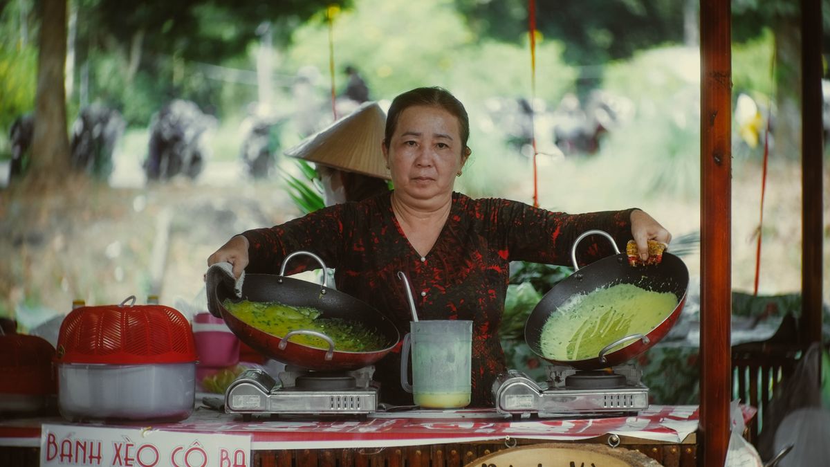 A street-food vendor cooking banh xeo in a pan