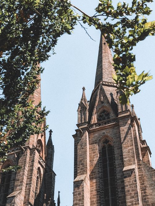 Free Stunning view of Marburg Cathedral's gothic spires framed by lush trees against a clear sky. Stock Photo