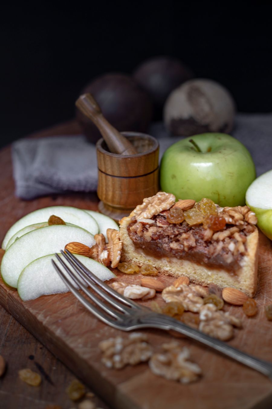 A slice of walnut tart surrounded by walnuts
