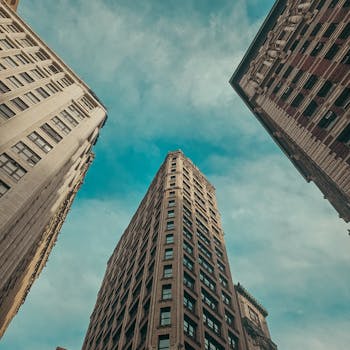 Cinematic view looking up at Manhattan skyscrapers against a dramatic sky.