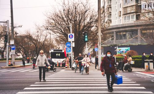 Free Pedestrians cross a bustling intersection in Beijing, showcasing everyday urban life. Stock Photo