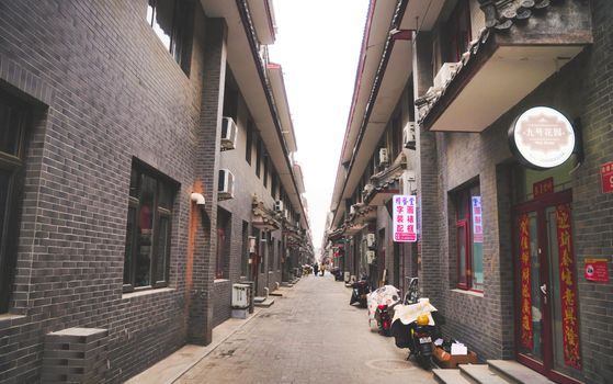 Explore a traditional alleyway in Beijing, showcasing gray brick architecture and local signage.